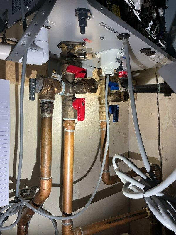 Performed comprehensive tankless water heater flush and fill maintenance service. Accessed unit's internal components, verified proper operation of isolation valves with red and blue handles, and flushed system to remove mineral buildup and sediment. Inspected circuit boards, electrical connections, and copper piping for proper function and secure mounting, confirming all components operational upon completion.
