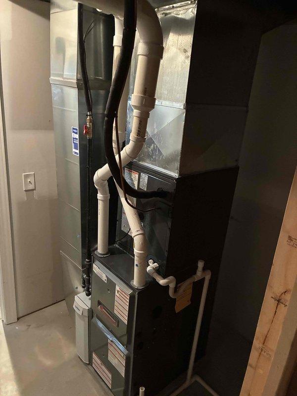Completed full HVAC system installation including 96% efficiency furnace and air conditioning unit in residential basement utility space. Installation included proper configuration of air handler, evaporator coil, refrigerant lines with copper fittings, PVC condensate drainage system, flexible ductwork connections, and all necessary electrical components. All equipment mounted, leveled, and secured according to manufacturer specifications with proper clearances maintained for service access and code compliance.