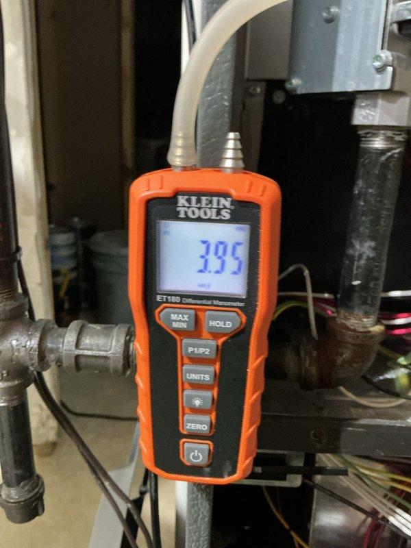 Completed scheduled heating maintenance on residential gas furnace system. Performed comprehensive inspection of furnace unit, verified proper operation of all safety controls, and checked venting system integrity including PVC condensate drain lines. Utilized Klein Tools ET180 differential manometer to measure system static pressure, recording 395 reading to verify airflow performance within manufacturer specifications. Inspected ductwork connections, plenum assembly, and all mechanical components for proper clearances and secure mounting. System operating normally with no deficiencies noted.