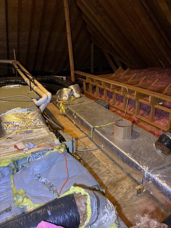 Conducted comprehensive estimate for complete HVAC system replacement due to non-functional air conditioning unit. Evaluated existing outdoor condenser units positioned on stone bed against residential exterior, assessed attic-mounted air handler and ductwork system, and documented current equipment configuration including refrigerant line routing and drainage components. Provided full system replacement options to restore cooling functionality.