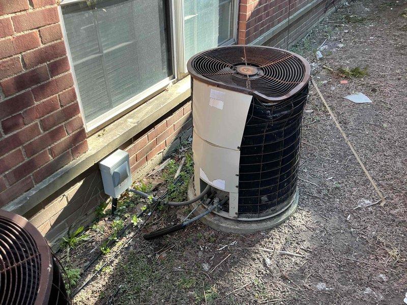 Conducted estimate for HVAC system replacement at rental property where existing outdoor condenser unit sustained damage from fallen gutter. Unit exhibited extensive rust on fan guard, weathered housing, and displaced components scattered on concrete pad, indicating compromised structural integrity and operational reliability. Assessed complete system replacement needs and provided options to property owner for new equipment installation.