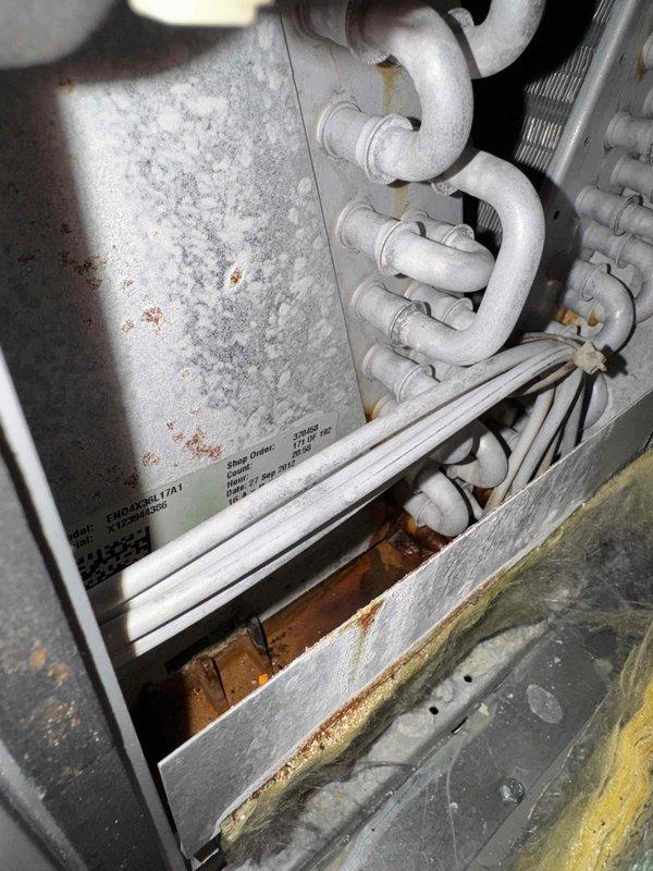 # HVAC Cooling Maintenance Completed

Performed comprehensive cooling system maintenance on residential HVAC unit. Upon inspection, discovered severely frosted evaporator coil assembly indicating restricted airflow or low refrigerant charge. Observed significant rust accumulation in condensate drain pan and base components, along with mineral deposit buildup affecting drainage. Documented condition of refrigerant lines showing age-related discoloration. Inspected control board assembly and electrical connections, verifying all wire terminations secure and system controls functioning properly. Unit requires follow-up service to address frosting issue and drainage concerns.
