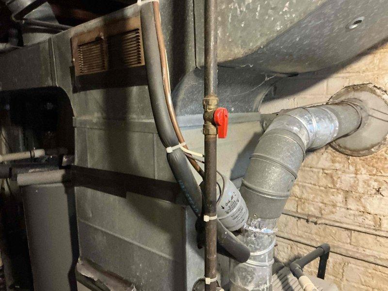 Completed HVAC system replacement estimate for air conditioning unit totaled from damage. Documented existing furnace/air handler installation in basement utility area, including evaporator coil with aluminum fins, refrigerant line routing with proper insulation and mounting, ductwork configuration, and overall system layout. Photographed current equipment condition and mechanical room setup to provide comprehensive assessment for replacement options.