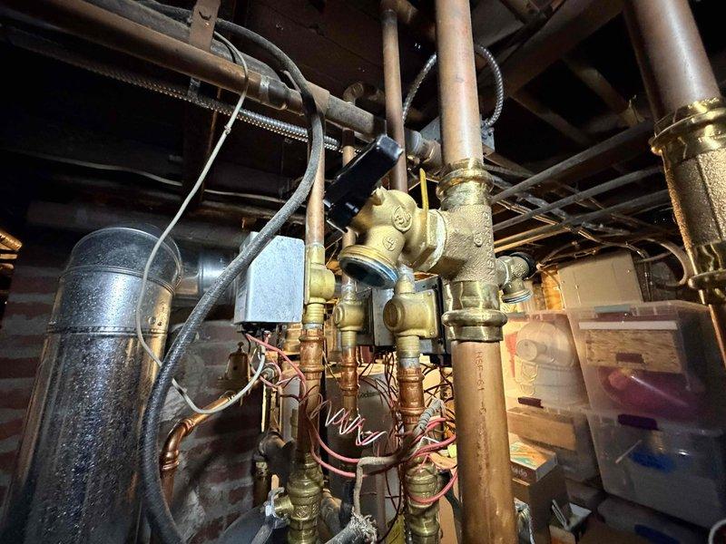 Responded to customer report of boiler leak in basement mechanical room. Upon arrival, conducted thorough visual inspection of boiler system and associated piping infrastructure. Examined copper piping assembly, brass valve connections, and fittings throughout the vertical and horizontal runs. Inspected expansion tank, pressure relief components, and all visible connection points for signs of active leaking or moisture accumulation. Documented existing conditions with photographic evidence showing complete piping configuration, valve assemblies, and mechanical equipment layout. System components including copper lines, flexible connectors, and control mechanisms were assessed for proper installation and potential failure points.