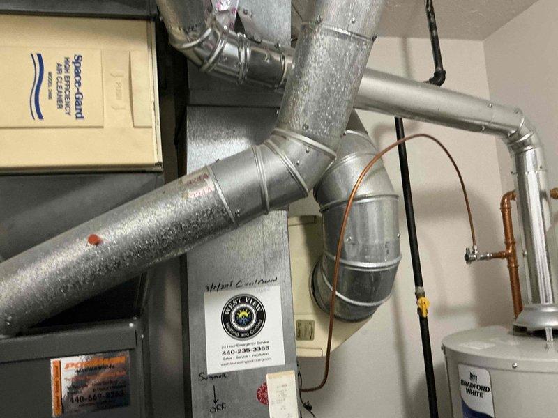 Completed comprehensive estimate for full HVAC system replacement including furnace and air conditioning unit located in first-floor utility closet. Assessed existing equipment configuration featuring Space-Gard air filtration system, galvanized metal ductwork with visible condensation, copper refrigerant lines, and beige air handler unit, documenting current installation layout and providing customer with replacement options for complete heating and cooling system upgrade.