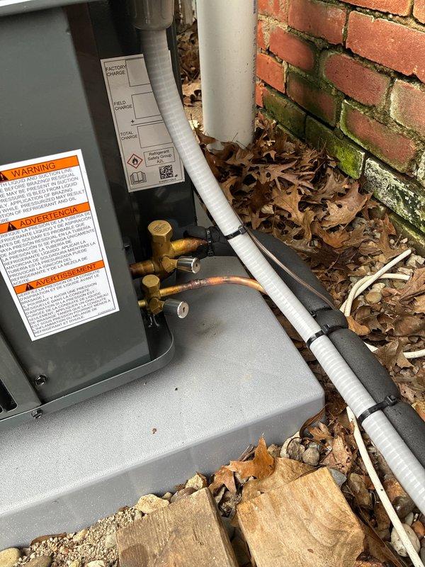 Completed outdoor air conditioning unit installation on exterior brick wall with proper refrigerant line routing, electrical conduit installation, and equipment mounting on concrete pad. Performed system pressure testing and verification using digital manometer to ensure proper refrigerant charge and system operation within manufacturer specifications.