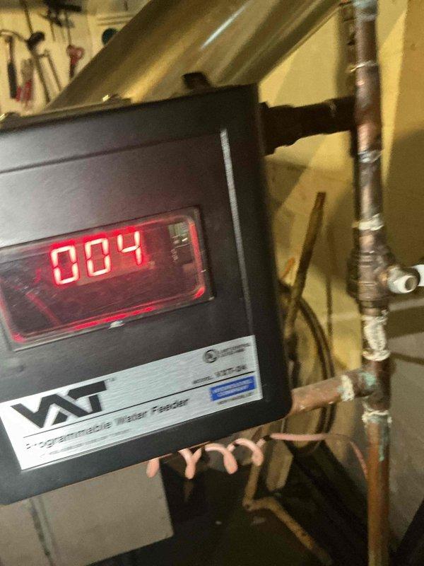 Completed scheduled preventive maintenance on water boiler heating system as part of ongoing recurring service program. Inspected boiler components, piping infrastructure, and control systems including programmable water feeder unit displaying normal operational readings. Observed significant copper pipe corrosion with green patina buildup on elbow joints and connections, documented conditions with photographs for maintenance records, and verified system operational status upon completion.