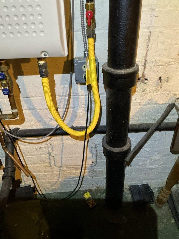 Completed comprehensive electrical inspection of residential service panel and utility area. Documented all circuit breaker configurations, wiring connections, and main breaker assembly with four terminal connections. Inspected electrical conduit routing, junction boxes, and wire management throughout the mechanical space. Verified proper installation of flexible metal conduit and assessed overall electrical system condition. Photographed panel interior showing organized wire bundling in multiple colors and documented surrounding utility connections including HVAC components, plumbing lines, and gas service lines for record-keeping purposes.