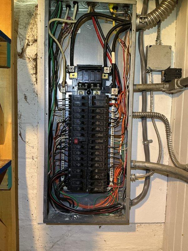 Completed comprehensive electrical inspection of residential service panel and utility area. Documented all circuit breaker configurations, wiring connections, and main breaker assembly with four terminal connections. Inspected electrical conduit routing, junction boxes, and wire management throughout the mechanical space. Verified proper installation of flexible metal conduit and assessed overall electrical system condition. Photographed panel interior showing organized wire bundling in multiple colors and documented surrounding utility connections including HVAC components, plumbing lines, and gas service lines for record-keeping purposes.