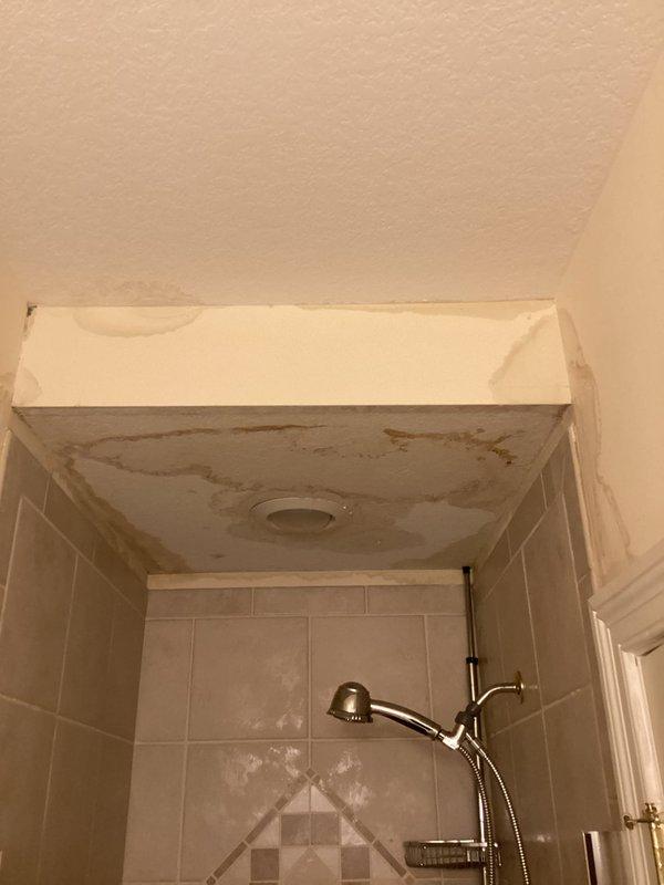 Responded to emergency water leak call with reported ceiling damage above shower stall. Upon arrival, documented extensive water damage to shower ceiling with visible discoloration, staining, and potential mold growth, along with corroded plumbing fixture in adjacent floor area showing significant rust, mineral deposits, and deteriorated surrounding subflooring. Photographed affected areas for documentation and further assessment by appropriate trades for repair.