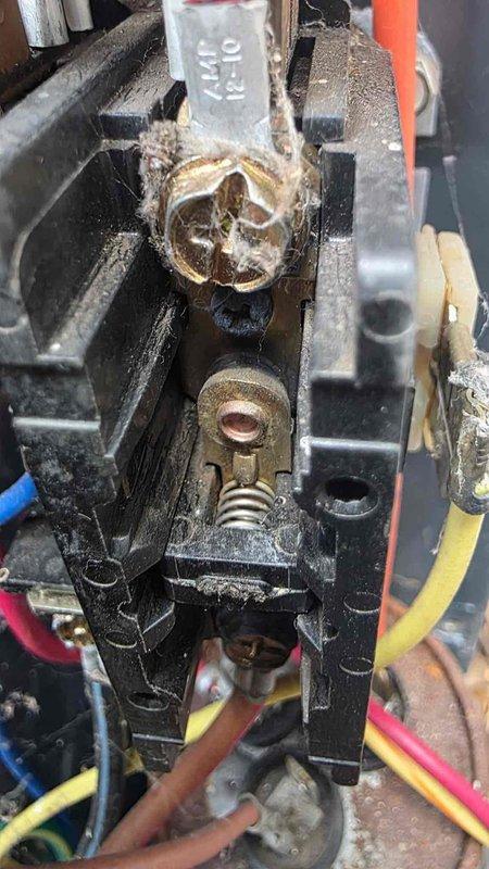 Completed comprehensive maintenance service on dual HVAC systems including heating and cooling equipment. Performed diagnostic testing on outdoor condenser unit with digital multimeter to evaluate capacitor performance and verify proper electrical function. Inspected internal fan assembly and motor components with top grille removed for thorough access. 

Identified severely corroded and deteriorated brass terminal connector showing evidence of overheating and electrical arcing damage with significant oxidation buildup. Terminal exhibited green and brown corrosion with melted metal around edges indicating previous thermal stress. Assessed electrical connections including red, yellow, blue, and brown wire terminations on black housing assembly. Documented excessive dirt, grime, and debris accumulation throughout electrical components affecting system reliability and performance. 

Conducted full system evaluation per maintenance protocol to ensure safe and efficient operation of both he