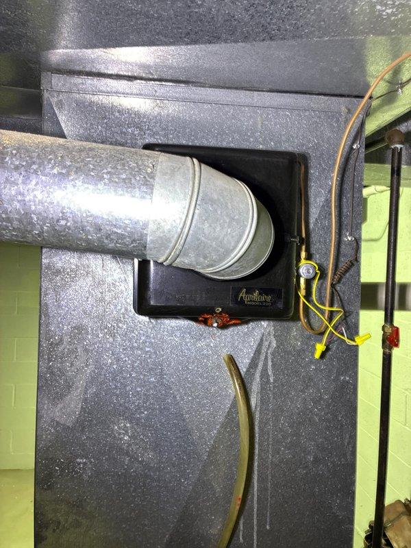 Completed comprehensive evaluation of upstairs HVAC system for full replacement options. Documented existing air handler installation showing plenum assembly with Aprilaire components, flexible ductwork connections, and associated electrical panel in utility closet. Assessed current system configuration including ductwork transitions, insulated plenum box, and copper refrigerant lines. Observed significant condensation on metallic surfaces indicating active cooling operation and temperature differential. Photographed electrical service panel, plumbing infrastructure, and complete HVAC component layout to provide detailed replacement specifications and equipment sizing recommendations for complete system upgrade.