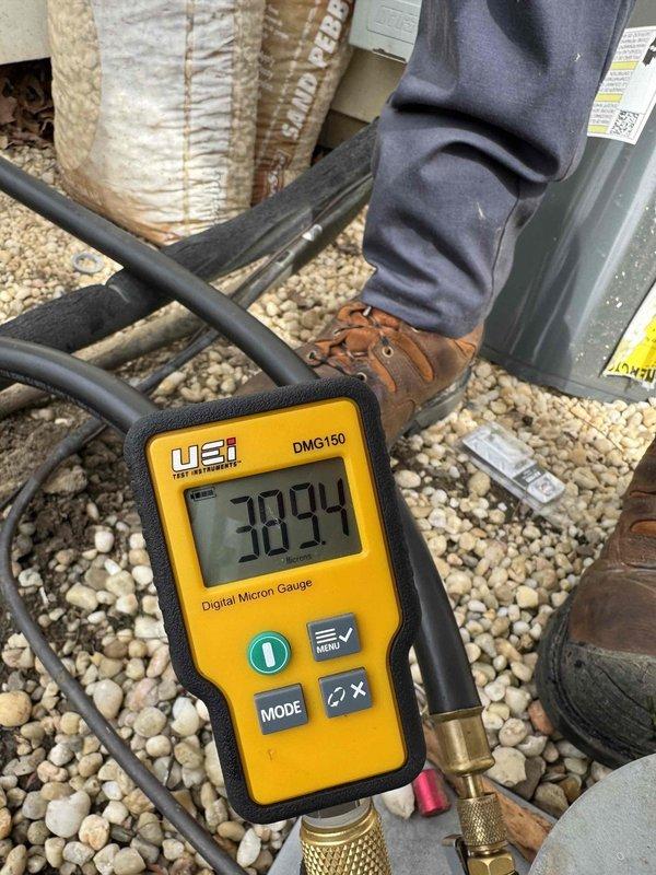 Performed leak search on HVAC system using digital micron gauge to diagnose refrigerant loss. Located significant corrosion on refrigerant piping and fittings, with heavy rust buildup on connection points indicating the source of the leak. Documented system condition showing deteriorated copper lines and corroded service ports requiring attention to restore proper system operation.