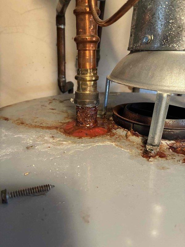 Responded to no hot water call and performed diagnostic inspection of tanked water heater. Upon examination, found evidence of significant internal corrosion, mineral deposits, and water leakage at the base of the unit around copper supply line connections, indicating tank failure. Verified gas burner assembly was operational with proper flame characteristics. Due to extensive rust damage and compromised tank integrity, recommended and completed full water heater replacement to restore hot water service.