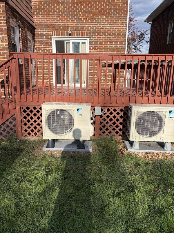 Completed installation of Daikin ductless mini-split system consisting of one indoor wall-mounted air handler unit and one outdoor condenser unit. The outdoor unit was positioned on a concrete pad in the yard area, with refrigerant lines and electrical connections properly routed to the interior air handler mounted on the wall, ensuring efficient operation of the single-head mini-split system.