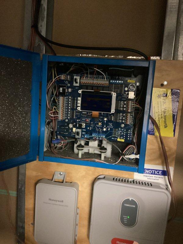 Responded to service call for unusual noise coming from circuit board in HVAC control panel. Inspected blue electrical enclosure containing zone control system with multiple circuit boards, relay modules, and associated wiring connections. Examined Honeywell zone control modules and display interfaces mounted below main panel. Verified all wire terminations were secure, checked for loose components or vibrating relays that could cause audible noise. Assessed overall system operation and confirmed proper functionality of control boards and connected devices.