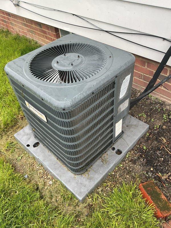 Responded to service call for AC unit inspection following storm damage to equipment and concrete pad. Performed thorough visual assessment of outdoor condenser unit and surrounding installation. Inspected condenser coils, fan assembly, cabinet integrity, electrical conduit, and refrigerant lines for storm-related damage. Verified concrete pad stability and levelness. Documented equipment condition with photographs showing unit operational status, exterior housing, fan grille assembly, and mounting configuration. Unit showed normal weathering consistent with age but no visible storm damage to critical components. Electrical connections and conduit routing intact with no signs of impact or displacement.
