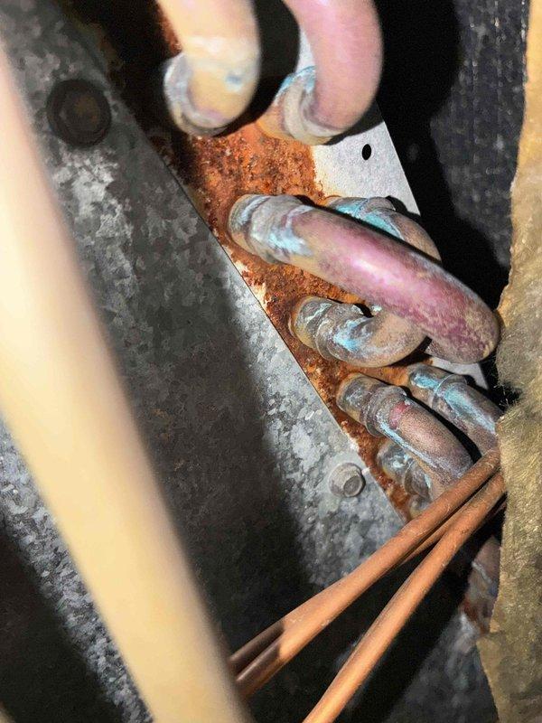 # HVAC No Heat Service Call

Responded to no heat complaint on residential furnace system over 10 years old. Upon arrival, coordinated with tenant prior to entry as requested. Conducted thorough system inspection and diagnosed heating failure. Visual assessment revealed extensive corrosion throughout critical system components, including severely rusted mounting hardware and deteriorated copper refrigerant lines showing advanced oxidation. Metal brackets and connection points exhibited significant rust penetration compromising structural integrity. Equipment displayed signs of prolonged moisture exposure and age-related deterioration consistent with end-of-life conditions. Documented existing conditions with photographic evidence showing corroded chain assembly, perforated mounting panels, galvanized ductwork surfaces, and oxidized copper piping connections with characteristic green-blue patina. System components showed wear patterns and corrosion levels indicating lack of preventative