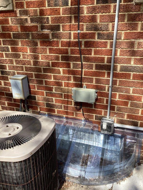 Conducted site assessment of existing outdoor AC condenser unit for relocation and reinstallation. Customer requires unit to be temporarily removed and relocated to accommodate concrete pad replacement and re-pouring work. Documented current installation configuration including electrical connections, conduit routing, and positioning against exterior brick wall. Unit is currently mounted on weathered concrete pad with electrical disconnect boxes and conduit properly installed on wall. Provided quote for disconnection, removal, temporary protection during concrete work, and reinstallation of condenser unit once new pad is cured and ready for equipment placement.