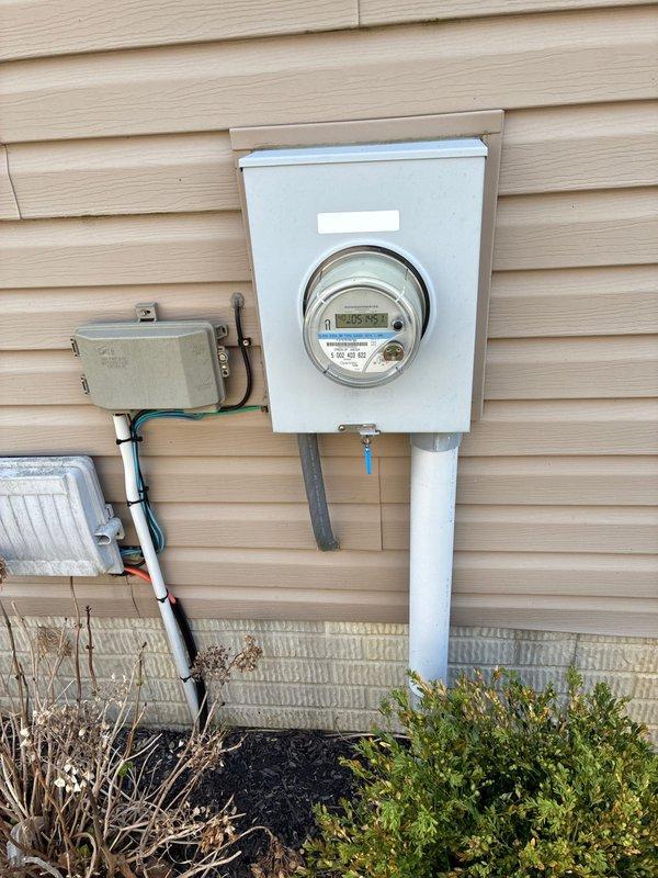 Conducted comprehensive site evaluation for complete HVAC system replacement at residential property. Documented existing exterior condensing unit with louvered metal housing positioned on ground-level mulch bed, along with electrical service infrastructure including digital meter assembly and associated conduit routing on building exterior. Provided customer with full system replacement options based on current equipment assessment and site conditions.