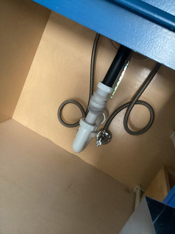 Provided plumbing estimate for replacing flexible drain assemblies with solid PVC drain lines and P-traps in three bathroom locations: master bath, first floor bath, and second floor bath. Estimate included sealing an access hole in the second floor bathroom using expanding foam insulation, and replacing a wye drain fitting under the stairs with solid pipe configuration. Documented existing plumbing conditions showing current flexible drain connections and PVC drainage assemblies secured with hose clamps.