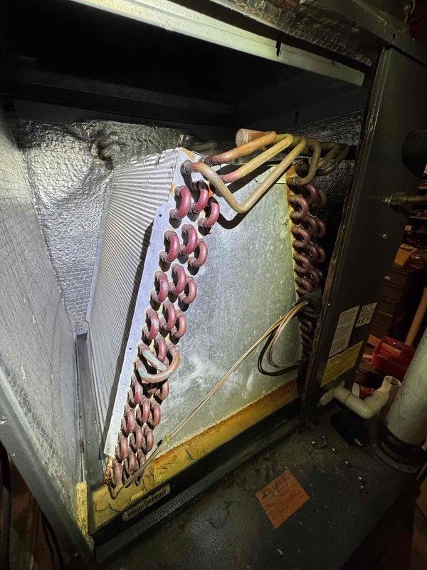 Performed comprehensive tune-up on residential HVAC system and discovered severe ice buildup on evaporator coil assembly, indicating restricted airflow or potential refrigerant issues requiring immediate attention. Inspected outdoor condenser unit and documented significant leveling concerns with unit leaning precariously toward radon mitigation system, creating potential safety hazard and compromising operational efficiency. Recommended corrective action for both frozen evaporator coil and condenser leveling to restore proper system function and prevent equipment damage.