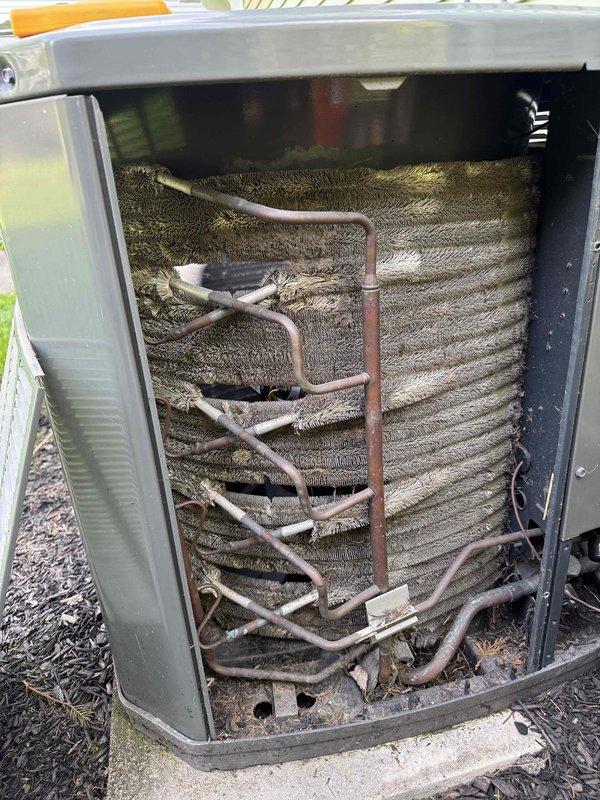 Completed preventative maintenance service on two HVAC cooling systems. Performed thorough inspection of outdoor condenser unit, accessing internal components to evaluate evaporator coil condition, refrigerant line integrity, and overall system operation. Observed moderate dust and debris accumulation on coil fins with some surface oxidation consistent with normal outdoor exposure. Checked refrigerant lines and insulation for wear and proper installation. Evaluated indoor air handler unit, noting active condensation on exterior surfaces indicating normal system operation during cooling mode. Measured temperature differential across system components using digital diagnostic equipment to verify proper cooling performance. Cleared debris from base of outdoor unit and documented system conditions through photographic records for maintenance history.