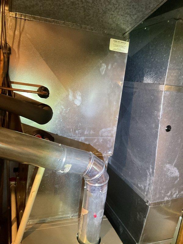 Performed comprehensive preventive maintenance on residential Carrier HVAC cooling system. Inspected internal components including refrigerant lines, electrical connections, and burner assembly with all systems found to be operating within normal parameters. Documented equipment condition through photographic records showing furnace unit with exposed mechanical components and ductwork in basement installation.