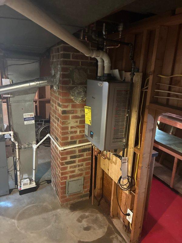Completed installation of wall-mounted tankless water heater in basement utility area with proper venting through existing brick chimney chase and PVC piping connections to main plumbing system. Unit was mounted securely, all gas and water connections were tested for leaks, and system was commissioned successfully with customer balance collected upon completion.