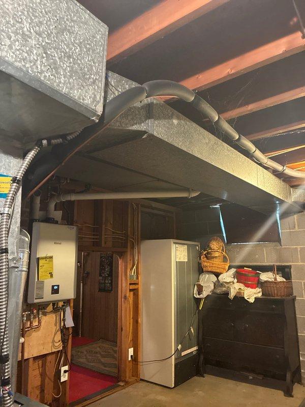 Completed installation of wall-mounted tankless water heater in basement utility area with proper venting through existing brick chimney chase and PVC piping connections to main plumbing system. Unit was mounted securely, all gas and water connections were tested for leaks, and system was commissioned successfully with customer balance collected upon completion.