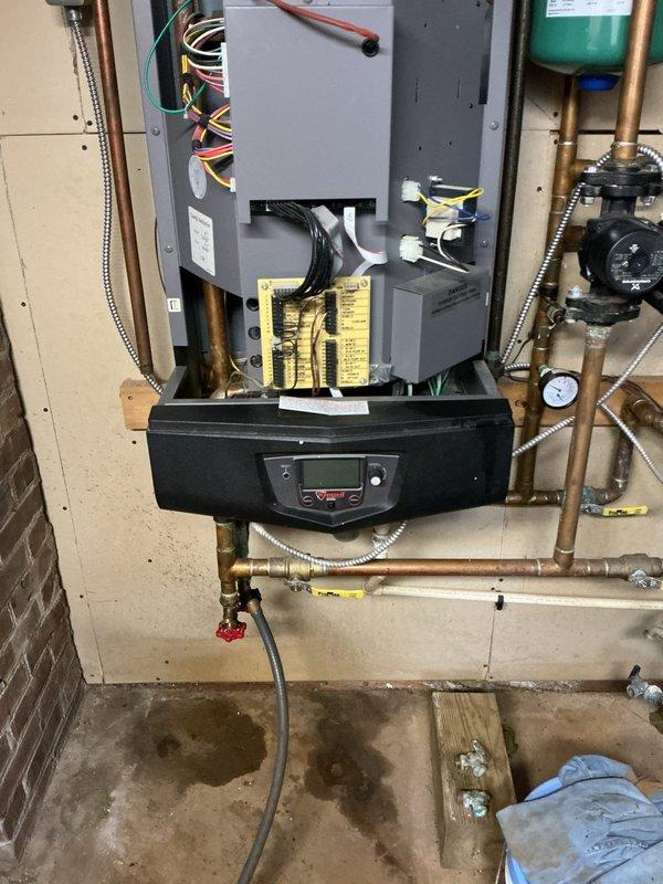 Completed installation and setup of new wall-mounted hydronic boiler system including all necessary piping connections, electrical integration, and safety components. Connected copper supply and return lines to the unit, installed expansion tank with pressure gauge, integrated zone valves, and established proper electrical connections to the control panel. Verified all plumbing connections are secure, system pressurized correctly, and digital control interface is functioning properly for optimal heating operation.