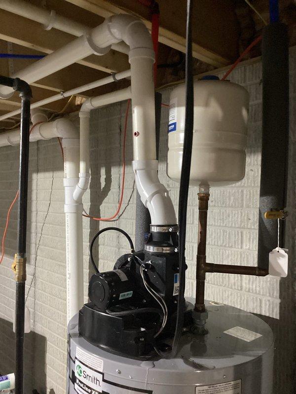 Responded to emergency service call for water heater leaking onto basement floor. Upon arrival, conducted thorough inspection of A.O. Smith tanked water heater system and associated plumbing connections. Identified source of leak, assessed condition of unit, pressure tank, and circulation pump assembly mounted on top of water heater. Documented existing installation including PVC supply and drainage lines, shut-off valves with red and blue handles, and overall mechanical system configuration for service records.