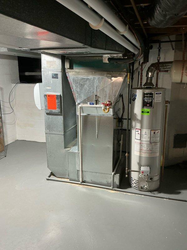 Performed comprehensive assessment of non-functional forced air HVAC system in residential basement and provided detailed replacement estimate including both air conditioning and heat pump options. Documented existing gray metal furnace/air handler unit with ductwork, electrical panel configuration, and system layout to present customer with equipment replacement alternatives for their heating and cooling needs.