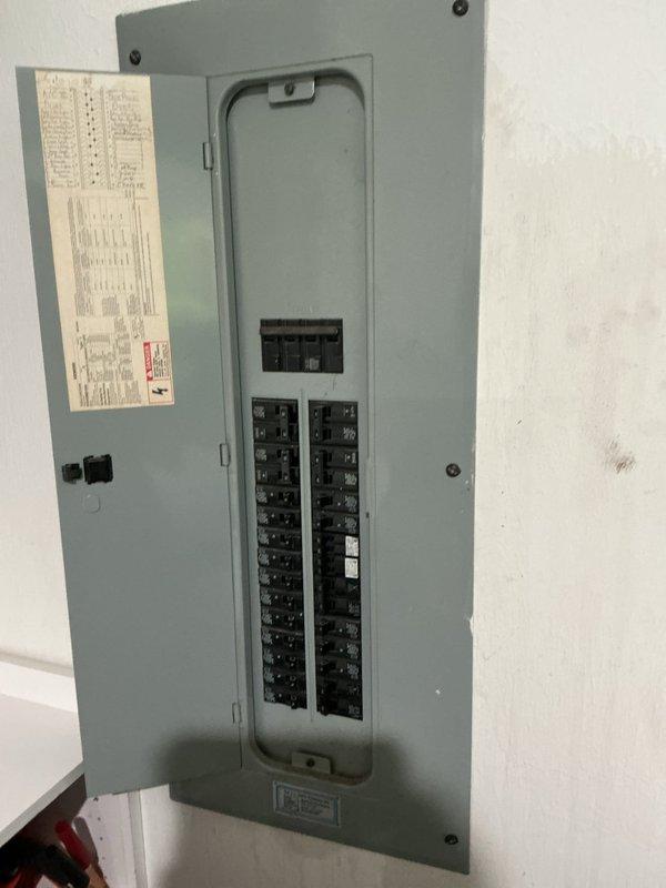 Completed electrical inspection of residential service panel and exterior utility connections. Panel inspection revealed properly organized circuit breakers in good working condition with main breaker functioning correctly. Exterior inspection identified weathered utility box with conduit connection requiring attention, and displaced outlet covers found on ground near building foundation that will need reinstallation to maintain proper weatherproofing and code compliance.