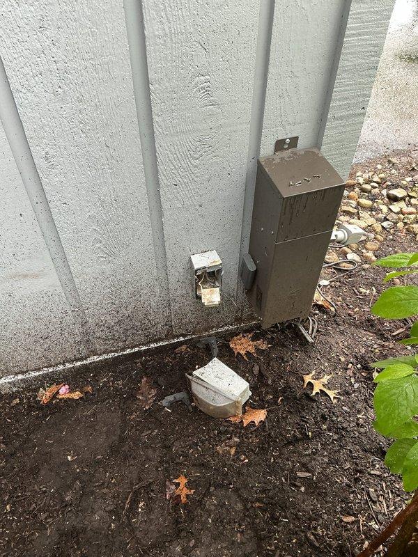 Completed electrical inspection of residential service panel and exterior utility connections. Panel inspection revealed properly organized circuit breakers in good working condition with main breaker functioning correctly. Exterior inspection identified weathered utility box with conduit connection requiring attention, and displaced outlet covers found on ground near building foundation that will need reinstallation to maintain proper weatherproofing and code compliance.