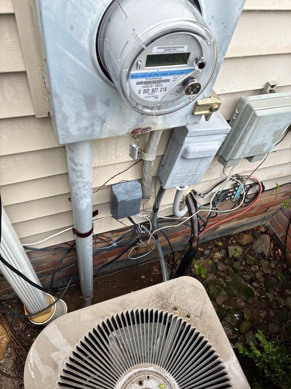 Conducted comprehensive site assessment for full HVAC system replacement, evaluating existing outdoor condensing unit and indoor equipment configuration. Documented current electrical service connection at exterior meter location, noting existing conduit routing and junction box placement for proper electrical sizing requirements. Assessed aging water heater with visible corrosion at base and evaluated mechanical room layout including existing ductwork, expansion tank configuration, and available space for new equipment installation. Provided multiple system replacement options addressing both heating and cooling components based on current equipment condition and utility infrastructure.
