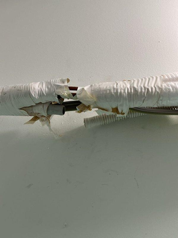 Responded to water leak complaint on upstairs heat pump mini-split system located in bedroom with drainage line running through closet. Upon inspection, identified compromised flexible ductwork with torn insulation and exposed interior components near the unit. Accessed mini-split air handler, opened front cover to inspect drain pan and condensate drainage system for blockages or overflow conditions causing water intrusion into closet area.