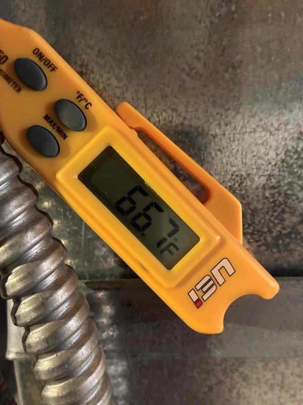 Completed routine HVAC cooling system maintenance and hot water tank inspection. Performed temperature diagnostics on ductwork showing 86.5°F readings, inspected electrical connections and terminal blocks within the unit, and evaluated overall system condition. Noted dust accumulation and minor surface oxidation on internal components typical of equipment in regular service.