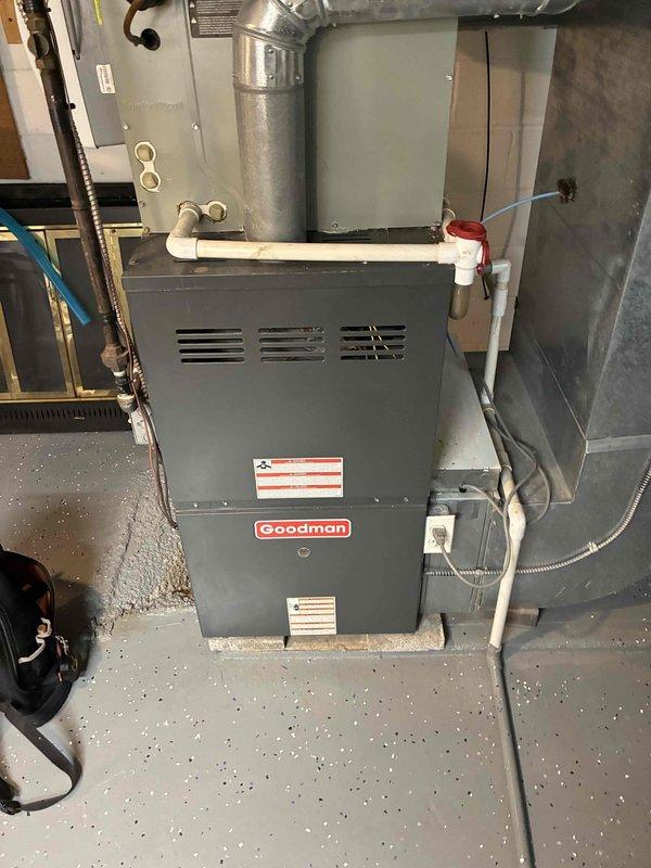 # HVAC Cooling Maintenance Summary

Completed scheduled preventive maintenance on residential cooling system as part of ongoing service agreement. Performed comprehensive inspection of Goodman furnace unit and associated air handling components, including blower motor assembly and ductwork system.

# Detailed Work Performed

Conducted thorough visual inspection of furnace unit positioned in basement utility area. Verified proper installation and mounting on concrete pad. Examined all manufacturer labels and safety information plates for compliance and legibility. Inspected metal ductwork components and plenum box for structural integrity and proper connections.

Performed detailed assessment of blower motor assembly within air handler housing. Inspected cylindrical motor body, mounting brackets, and manufacturer identification label. Verified blower wheel condition, noting light gray perforated design with radial slot pattern for optimal air movement. Examined all electrical connection