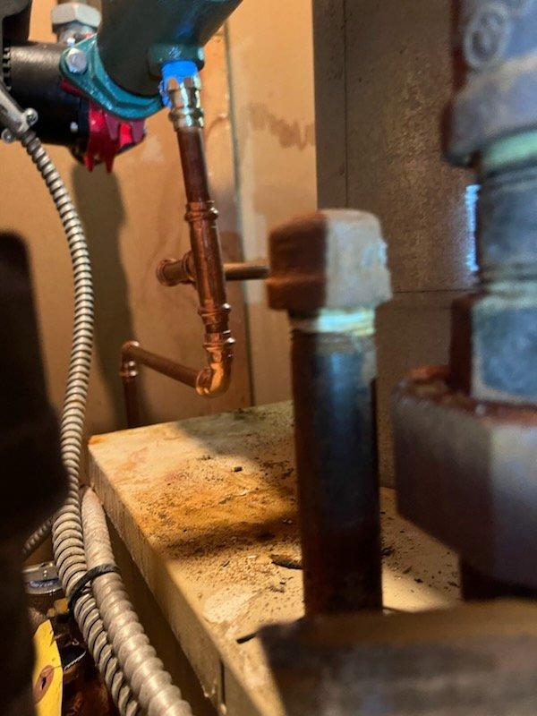 Completed boiler repair involving replacement of pressure reducing valve assembly. Installed new PRV with brass cap and adjustment mechanism on copper supply line. Applied thread sealant tape to threaded connections and soldered copper piping joints to ensure leak-free operation. Tested system for proper water pressure regulation and verified all connections for secure operation.