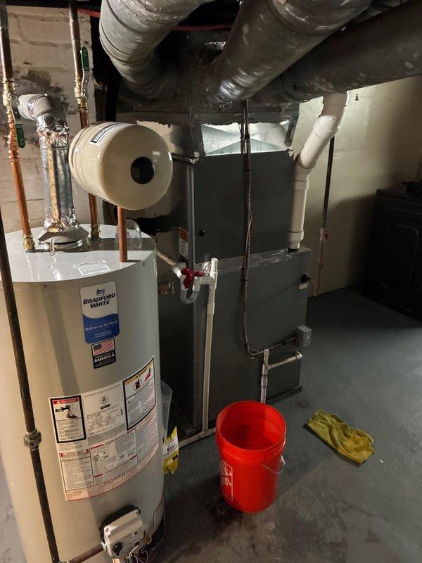 Completed comprehensive HVAC system evaluation for furnace replacement estimate in residential basement mechanical room. Assessed existing gray metal forced-air furnace with visible air filtration system, ductwork connections, and associated PVC condensate drainage piping. Documented current equipment configuration including Bradford White water heater, flexible ductwork distribution system, refrigerant line connections with brass fittings, and overall mechanical room layout. Provided homeowner with furnace replacement options while noting that existing air conditioning system is newer and in serviceable condition, allowing for furnace-only replacement to optimize cost-effectiveness while maintaining functional cooling equipment.