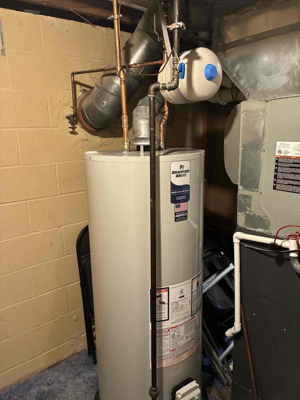 Completed installation of 50-gallon Bradford White residential water heater in basement utility area. Removed existing unit and installed new water heater with proper copper supply line connections, expansion tank, pressure relief valve assembly, and all required safety components per manufacturer specifications and local plumbing codes. Verified all connections for proper operation and tested system for leaks.
