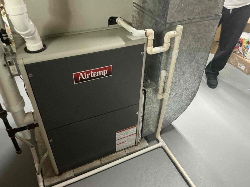 Conducted comprehensive assessment of existing HVAC system in basement utility area and presented full system replacement options. Evaluated current Airtemp furnace unit, associated ductwork infrastructure, and auxiliary components including PVC condensate drainage lines and venting systems. Documented existing equipment configuration with detailed photographic records showing furnace positioning, galvanized supply ductwork, plumbing connections, and overall mechanical system layout for replacement proposal development.