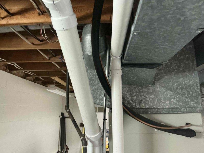 Conducted comprehensive assessment of existing HVAC system in basement utility area and presented full system replacement options. Evaluated current Airtemp furnace unit, associated ductwork infrastructure, and auxiliary components including PVC condensate drainage lines and venting systems. Documented existing equipment configuration with detailed photographic records showing furnace positioning, galvanized supply ductwork, plumbing connections, and overall mechanical system layout for replacement proposal development.
