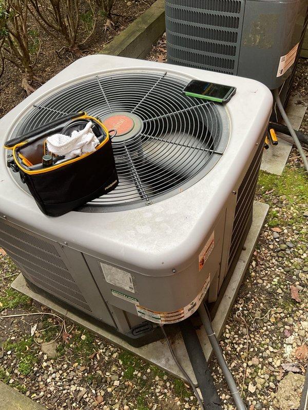 Completed comprehensive cooling maintenance on two residential air conditioning systems. Performed standard preventive maintenance procedures including inspection of both outdoor condenser units, one beige/tan unit showing age-related rust on lower casing and one gray Amana unit mounted on concrete pad against brick wall. Verified proper operation of all components, checked electrical connections at disconnect boxes, and inspected refrigerant line sets. Both systems operational and ready for cooling season.
