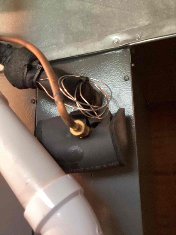 Completed scheduled cooling system maintenance on residential HVAC unit. Inspected exterior condenser disconnect box, refrigerant line connections, and condensate drain system. All components operating within normal parameters, copper refrigerant lines and PVC drainage showing proper installation and no signs of leakage or deterioration.