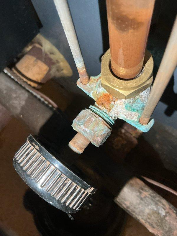 Responded to service call for reported boiler leak. Upon inspection, identified active water seepage at corroded brass compression fitting on copper supply piping. Fitting and surrounding pipe connections exhibited severe oxidation with heavy verdigris buildup and mineral deposits, indicating prolonged moisture exposure. Documented extensive corrosion at threaded union connections requiring replacement to resolve leak and prevent system failure.