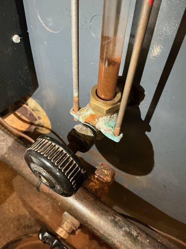 Responded to service call for reported boiler leak. Upon inspection, identified active water seepage at corroded brass compression fitting on copper supply piping. Fitting and surrounding pipe connections exhibited severe oxidation with heavy verdigris buildup and mineral deposits, indicating prolonged moisture exposure. Documented extensive corrosion at threaded union connections requiring replacement to resolve leak and prevent system failure.