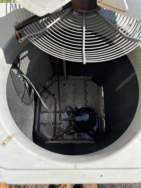 Completed scheduled cooling system maintenance on outdoor condensing unit. Removed top access panel to inspect internal components including compressor, fan motor, and electrical connections. Cleaned accumulated dirt and debris from fan guard, mounting brackets, and internal housing surfaces. Verified proper operation of condenser fan and checked for signs of wear or corrosion on metal components and fasteners. All electrical connections were secure with no immediate concerns noted. Unit returned to normal operation following inspection and cleaning procedures.
