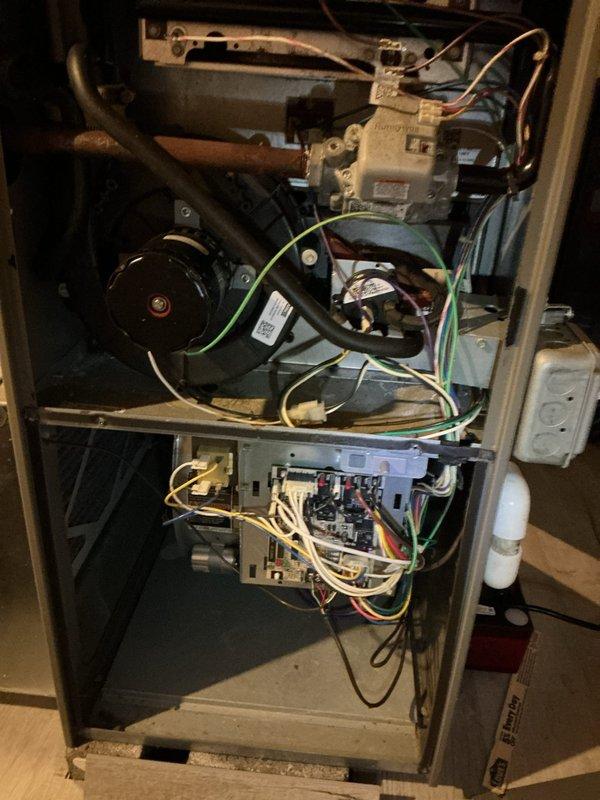 Responded to service call for furnace making noise at residential property. Upon arrival, performed diagnostic inspection of heating system. Removed access panels and examined internal components including blower motor assembly, gas valve, control board, and electrical connections. Verified system operation and observed LED indicators showing unit was powered and functional. Inspected blower motor for unusual sounds or mechanical issues as previously suggested by another contractor. Examined wiring connections throughout unit, noting various wire runs to control board and gas valve assembly. Documented equipment condition through photography for service records. All major components including blower motor, control board, and gas valve were inspected and operational at time of service.